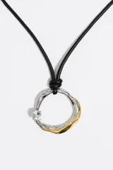 Collar de cordón negro con colgante circular de textura irregular en acabado bicolor plateado y dorado, adornado con un pequeño cristal transparente incrustado.