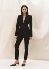 Pantalón de vestir negro, de corte ajustado y tobillero, con cierre frontal de cremallera y botón, trabillas para cinturón y bolsillos de ribete traseros.