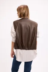 Chaleco de cuero sintético negro, con cierre frontal de botones a presión, bolsillos laterales y ruedo regulable con cordón elástico.