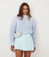 Short pollera de material sintético color celeste, con diseño cruzado en la parte delantera y cierre lateral con cremallera.