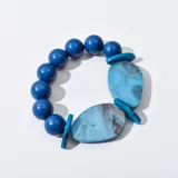 Pulsera elástica con cuentas redondas de color azul y cuentas planas de resina marmolada en tonos celeste y marrón.