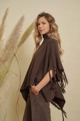 Poncho tejido de punto acanalado en color marrón chocolate, con cuello alto y diseño irregular con flecos en los bordes.