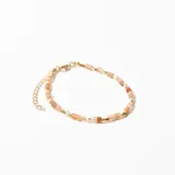 Pulsera de cuentas facetadas color durazno y doradas, unidas por hilo de tanza y cierre de mosquetón dorado con cadena de alargue.