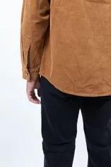 Camisa de pana color camel, de corte recto, con cuello abotonado y bolsillo en el pecho.