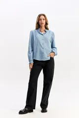 Blusa de algodón en color celeste, con textura sutil, cuello con volados y mangas largas con puños también decorados con volados. Presenta cierre frontal con botones.