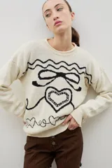 Buzo de cuello redondo con calce holgado, confeccionado en tejido de punto grueso con diseño jacquard de moña y corazones en contraste.