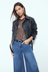 Remera de estilo deportivo con cuello en V y mangas cortas amplias. Presenta un diseño de rayas verticales en tonos marrones, blancos y líneas finas en fucsia, confeccionada en tejido de red.