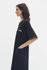 Vestido midi de algodón color negro, con cuello redondo, mangas cortas, costuras en contraste y bolsillos laterales.