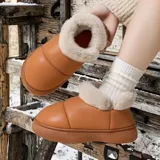Pantuflas botitas color tostado con diseño acolchado y plataforma, forradas con corderito sintético blanco en el interior y el cuello. Cuentan con una pequeña etiqueta decorativa en el lateral.
