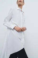 Camisa de popelín de algodón con cuello solapa, manga larga con puños y bajo asimétrico. Presenta cierre frontal con botones ocultos.