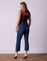 Pantalón jean azul oscuro, tiro alto, corte recto y terminación bootcut. Tiene bolsillos delanteros y traseros, pretina con pasadores, botón y cierre. Aplique de tachas en los laterales.