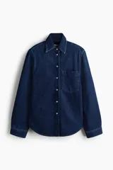 Camisa en denim de algodón con hombreras, cuello clásico, botones a presión nacarados, bolsillo frontal aplicado y bajo redondeado.