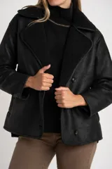 Chaqueta tipo gamulán de color negro con forro de corderito sintético al tono. Presenta solapas anchas, cierre frontal con botones y un diseño entallado al cuerpo.
