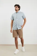 Camisa azul de manga corta, con cuello abotonado y bolsillo en el pecho.