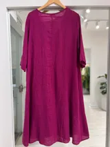 Vestido midi de lino color magenta, con escote en V, mangas tres cuartos y corte amplio y fluido.