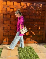 Cartera bandolera de cuero crudo con forro de tela, bolsillo frontal y bolsillo interno. Tiene correa larga regulable y manijas cortas de cuero marrón.