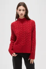 Polera de tejido de punto color crema, con cuello alto y diseño de trenzas verticales. Presenta mangas largas con puños acanalados y un corte holgado.