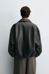 Cazadora bomber de corte relajado confeccionada en tejido efecto piel. Presenta cuello solapa, cierre frontal de cremallera, bolsillos laterales de vivo y puños y ruedo con elástico interior.