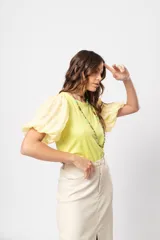 Blusa verde con cuello redondo y mangas cortas abullonadas.