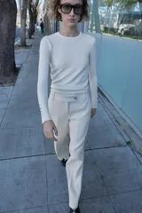 Pantalón blanco de tiro alto con pernera recta y pinzas marcadas en el frente. Cierre frontal con botón metálico dorado.