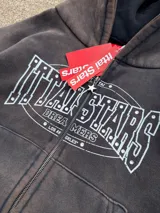 Campera canguro con cierre frontal, capucha y bolsillos tipo canguro, en tono marrón con efecto gastado vintage y estampa gráfica blanca con detalles de strass en el pecho.