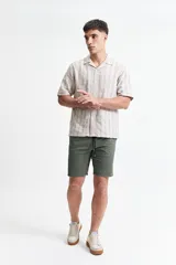 Camisa de manga corta a rayas verticales blancas y grises, con cuello camisero y corte recto. El modelo usa talle M.