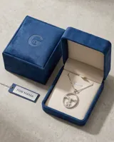 Dije circular de plata 925 con incrustaciones de circonias, que presenta la inscripción 'mama' en la parte superior y dos rosas detalladas en el centro.
