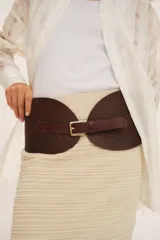 Faja ancha de cuero negro con textura granulada, diseño asimétrico en el cierre y hebilla metálica dorada.
