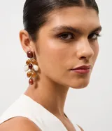 Caravanas medianas con diseño alargado, compuestas por múltiples piezas en forma de gota y óvalos de resina en tonos marrones, crema y blanco, engarzadas en metal dorado.