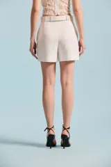 Short negro de tiro alto con cinto incorporado del mismo género con hebilla redonda forrada, bolsillos laterales y dobladillo en las piernas.