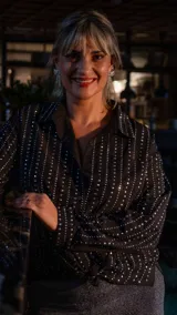 Camisa negra con cuello clásico, manga larga y cierre frontal con botones. Decorada con brillos plateados verticales.