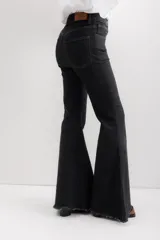 Jean de corte acampanado con cintura alta, confeccionado en denim azul oscuro. Presenta costuras en contraste y un acabado deshilachado en el ruedo.