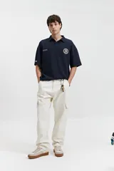 Remera polo color crema con logo bordado en el pecho, de corte amplio y mangas cortas.