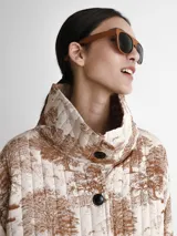 Saco acolchado con estampado toile de jouy en tonos beige y marrón, con cuello alto y cierre frontal con botones negros.