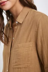 Camisa blanca de algodón con textura arrugada, corte clásico, cuello camisero, manga larga con puños abotonados y bolsillo de parche en el pecho.