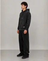 Canguro negro de corte holgado con capucha ajustable mediante cordones, bolsillo frontal tipo canguro y logo bordado en el pecho.