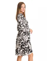 Vestido envolvente de seda fría estampado en blanco y negro, marca Luxology. Presenta escote en V cruzado, cintura elastizada con apliques metálicos en el lateral, manga larga entallada y ruedo asimétrico en el frente.