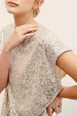 Remera plateada con lentejuelas, de manga corta y cuello redondo.