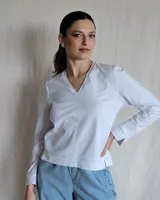 Remera de algodón color blanco, con escote en V y detalle de pespuntes decorativos en color beige. Presenta mangas largas y un corte recto con aberturas laterales en el ruedo.