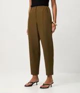 Pantalón carrot en crepé negro, de cintura alta, corte holgado en las caderas que se estrecha hacia los tobillos, con bolsillos laterales.
