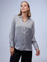 Camisa de satén estampado con diseño de cadenas en blanco y negro. Cuello con solapa, escote en V y abertura central con botones.