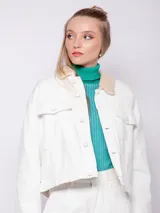 Campera de jean azul con interior forrado en corderito color crema. Presenta cuello camisero, cierre frontal con botones metálicos y dos bolsillos frontales con solapa.