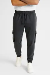 Babucha gris oscuro estilo cargo con cintura elástica y cordón de ajuste, bolsillos laterales con solapa y puños elásticos en los tobillos.