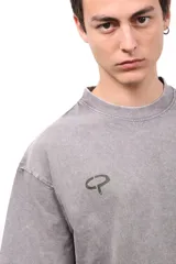 Remera de algodón con efecto lavado en color gris, de corte holgado y manga corta. Presenta un estampado cuadrado en la espalda con fondo marrón y círculos amarillos, junto con la inscripción CAPER.