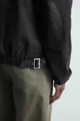 Cazadora de denim de algodón con efecto lavado, corte relajado, cuello de solapa en piel sintética a tono, cierre frontal con cremallera oculta por solapa con botones, bolsillos con cremallera en el pecho y mangas largas con puños abotonados.