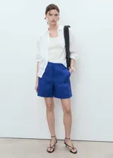 Short de tiro medio confeccionado en lino, con diseño recto, bolsillos laterales y cierre oculto de botón, gancho y cremallera.