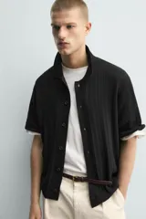 Camisa relaxed fit de punto tejida en hilatura con mezcla de algodón, color negro, con cuello solapa, manga corta y cierre frontal de botonadura.