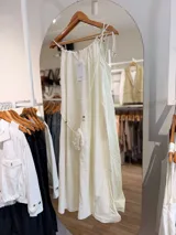 Vestido midi celeste de silueta amplia y fluida, con escote fruncido y tirantes finos decorados con cuentas de madera. Incluye una pequeña carterita colgante haciendo juego.