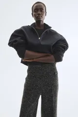 Pantalón de tiro alto de tweed negro con efecto melange, corte recto, bolsillos frontales tipo parche con botones y pliegues marcados.
