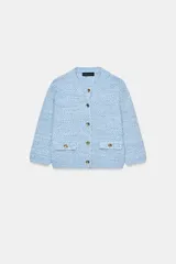 Chaqueta de punto en tono celeste, de cuello redondo, manga francesa y cierre frontal con botones dorados. Cuenta con bolsillos simulados con solapa y botones dorados en la parte delantera.